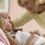 sick kid in bed while mom checks for fever